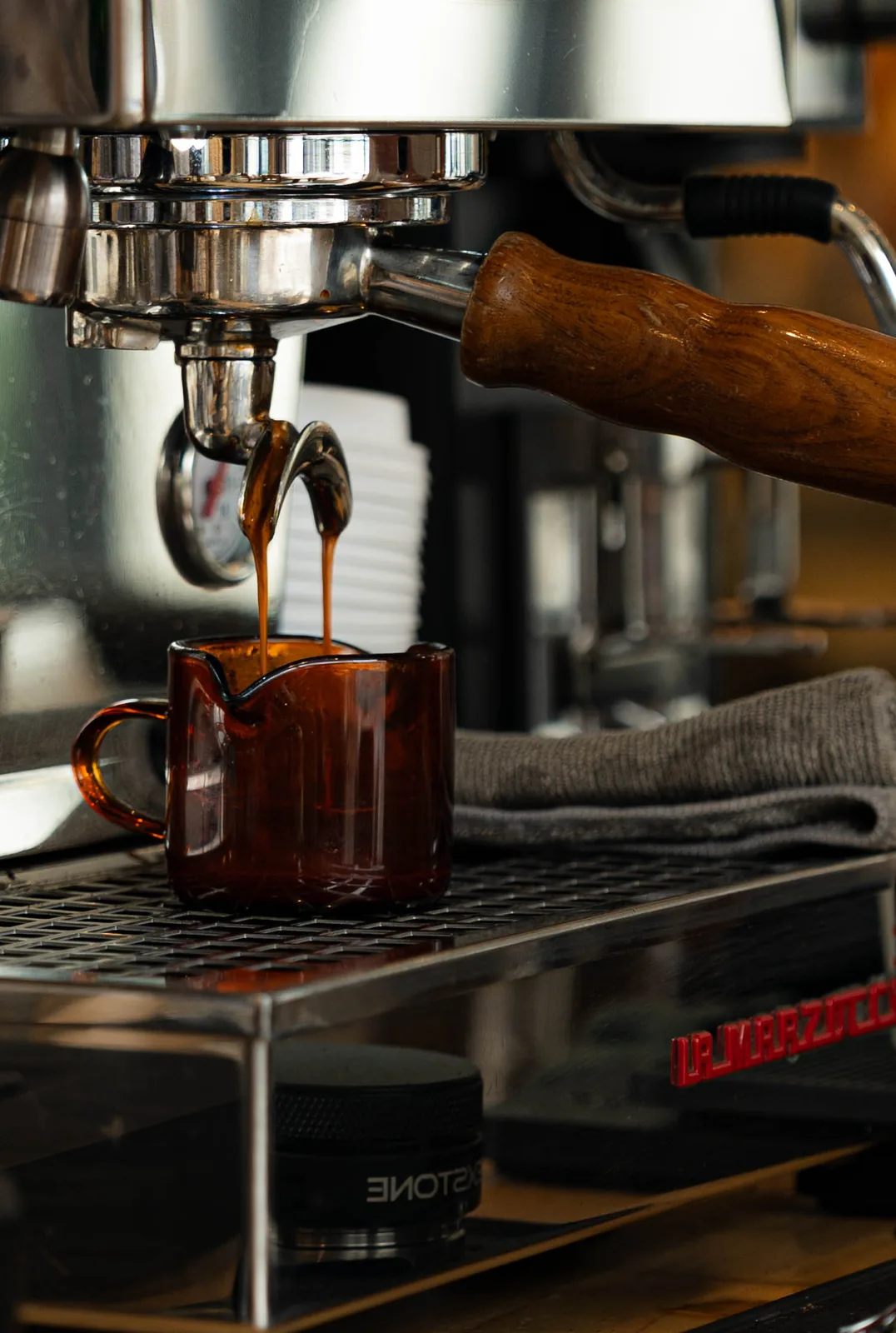 Espresso pouring into a small glass pitcher on the La Marzocco