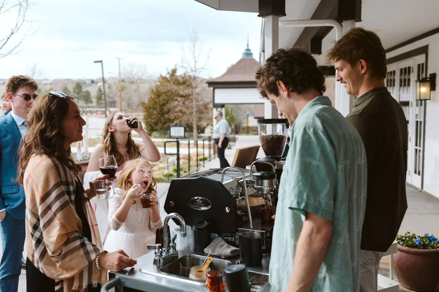Guests laughing with drinks at an outdoor party while Zado baristas work the machine
