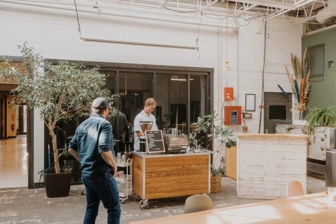 The Zado cart set up in a bright, plant-filled event space as a guest walks up